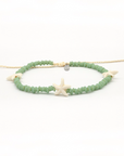 A beaded stretch bracelet featuring light green faceted beads, a central cream starfish charm, and small shell accents, displayed on a clean white background.