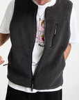Person wearing a black fleece vest over a white shirt with graphic design