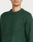 Green sweater worn by a person on a plain background