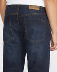Dark blue jeans with a brand patch on a white background