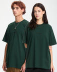 Two people wearing dark green t-shirts with a brand logo on a white background