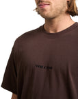 Man wearing a brown t-shirt with 'Volcom' logo on a white background