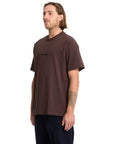 Man wearing a brown t-shirt with a logo on a white background