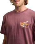 Man wearing a maroon Volcom t-shirt with a logo on a white background