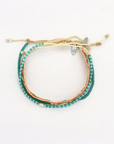 A multi-strand beaded bracelet featuring teal, orange, and cream threads, adorned with small white beads and a butterfly charm, displayed on a plain white background.