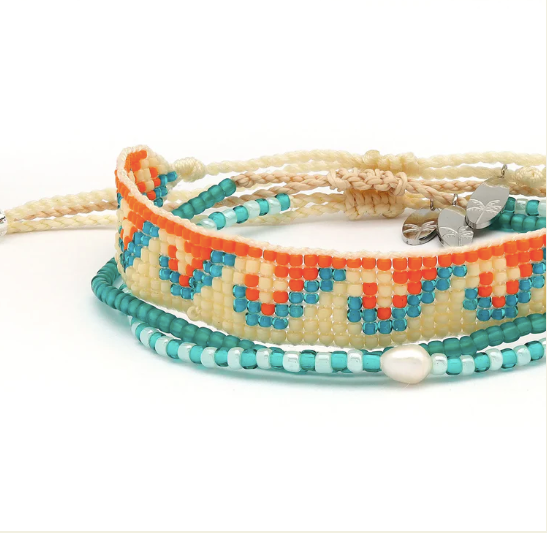 A set of three beaded bracelets stacked together on a white background. The top bracelet is made of cream cord with a small silver heart charm.