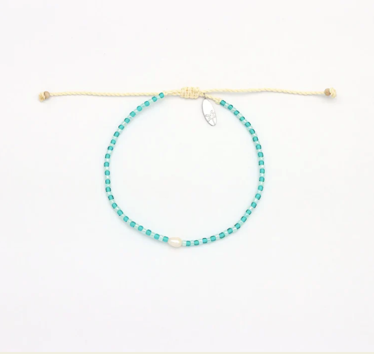 A beaded necklace with small turquoise-blue beads and a white central bead, suspended on a cream-colored adjustable cord with a small silver charm, shown on a plain white background.