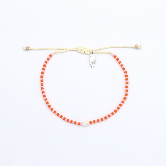 A beaded adjustable cord bracelet featuring bright orange-red round beads, a cream-colored adjustable rope closure with a knot, and a small silver-toned safety pin clasp, shown on a plain white background.