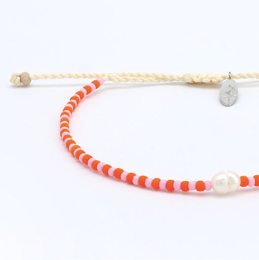 A beaded bracelet featuring alternating bright orange and light pink beads, accented by a single white pearl bead and a small silver-toned oval charm, on a white background.