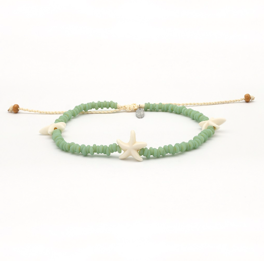 A beaded stretch bracelet featuring light green faceted beads, a central cream starfish charm, and small shell accents, displayed on a clean white background.