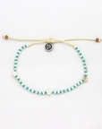 A beaded sliding cord bracelet featuring turquoise and white striped beads, white star charms, and a central silver-toned circular charm with a black design, displayed on a clean white background.