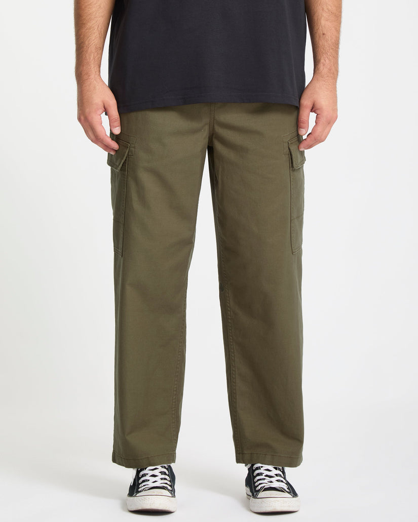Person wearing olive green Volcom cargo pants on a white background