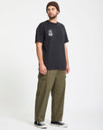 Man wearing a black Volcom t-shirt with a logo and green pants on a white background