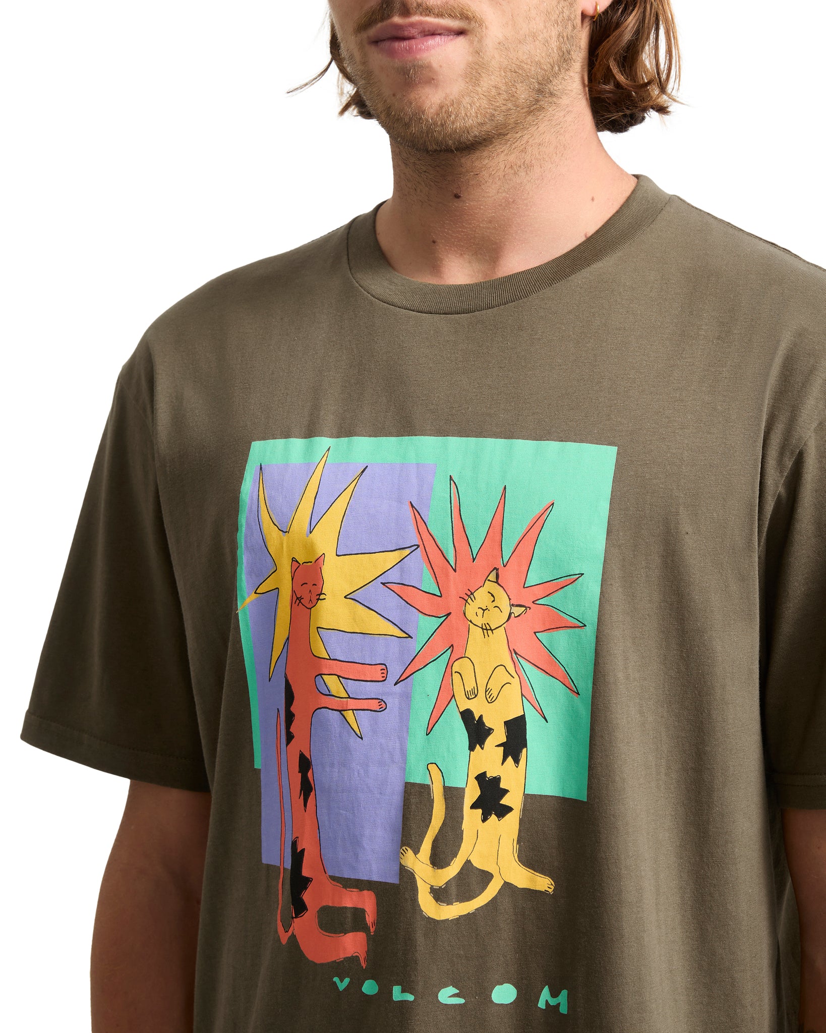 Person wearing a brown t-shirt with colorful graphic design and &#39;Volcom&#39; branding.
