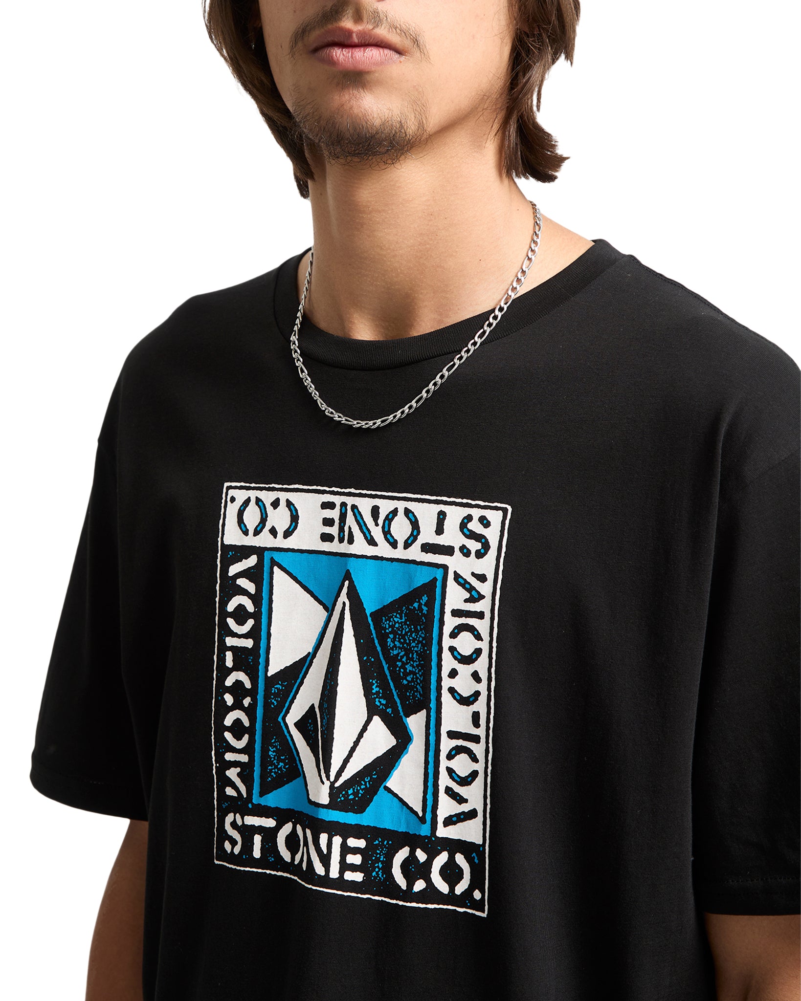 Person wearing a black Volcom t-shirt with a Volcom logo on a white background