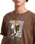 Person wearing a brown t-shirt with a Volcom logo