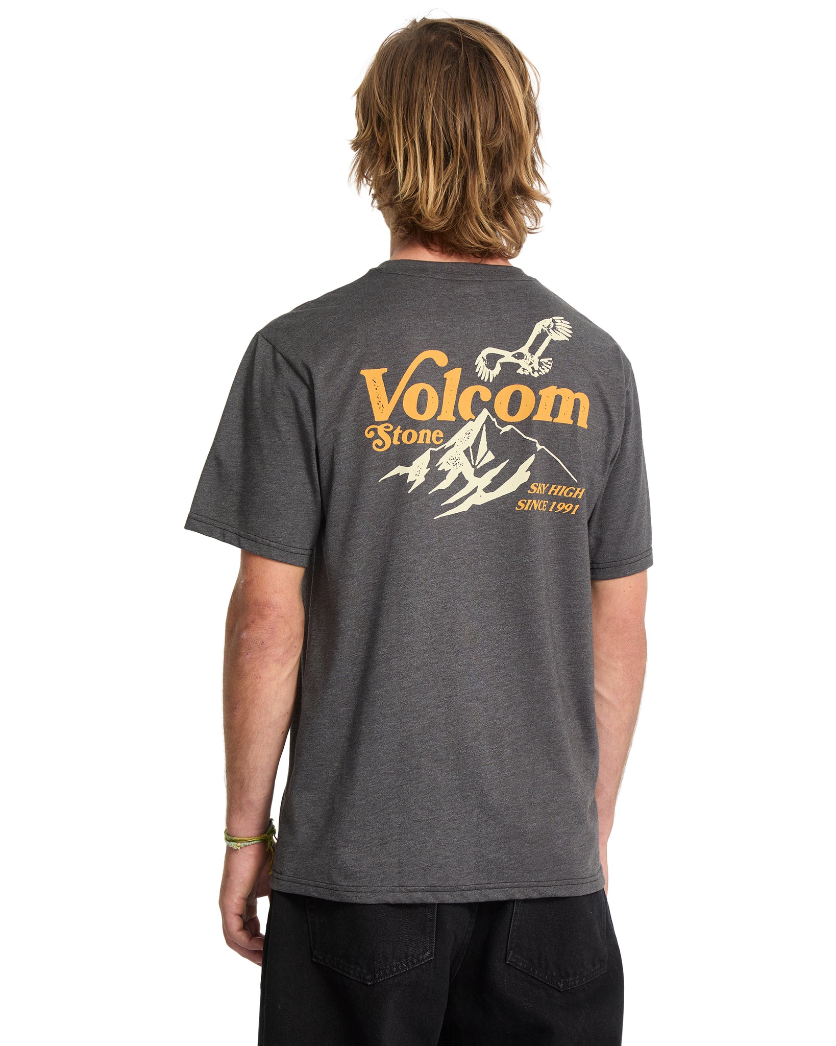 Person wearing a gray Volcom t-shirt with a mountain graphic on the back.