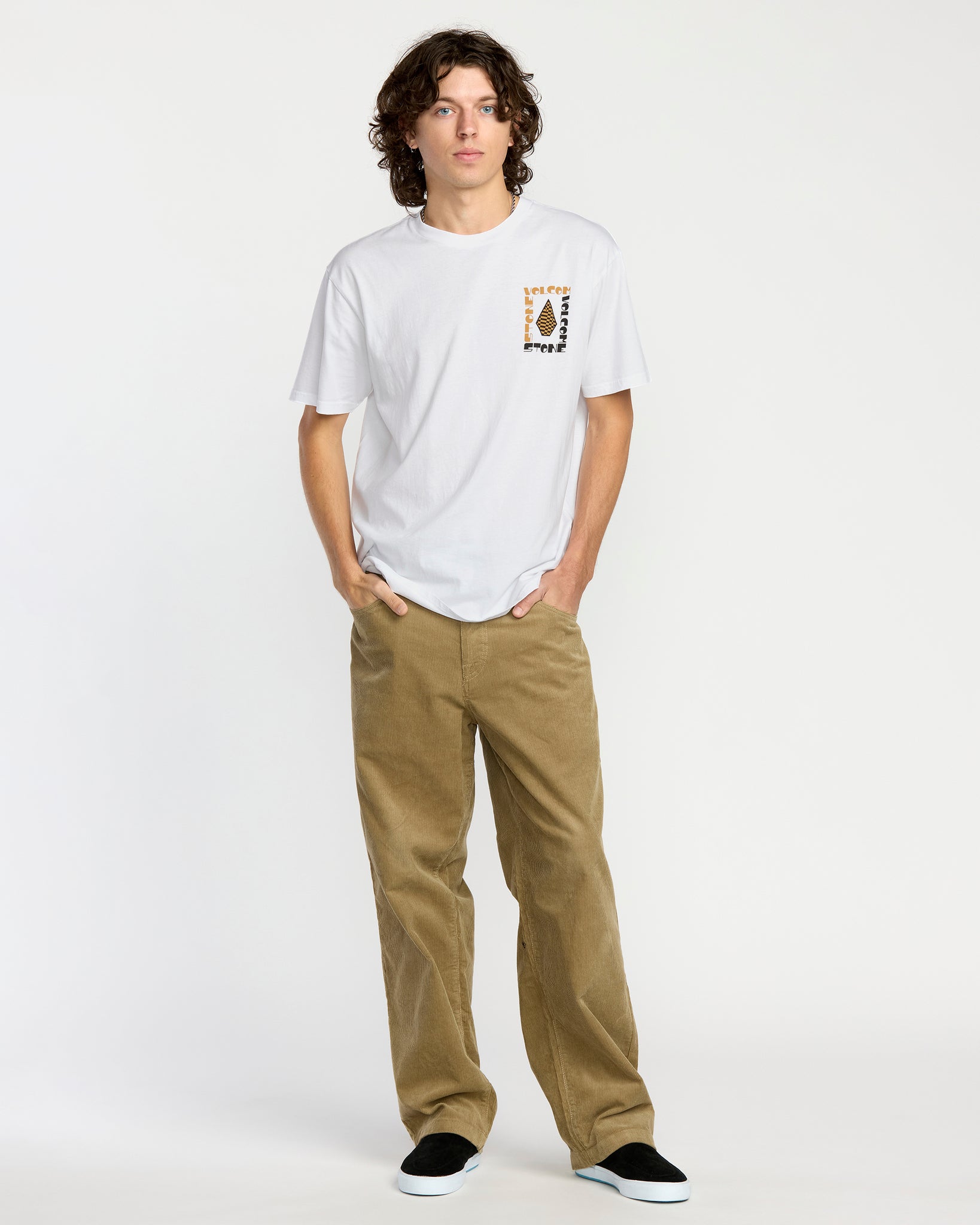 Man wearing a white t-shirt with a Voclom graphic design and brown pants on a white background