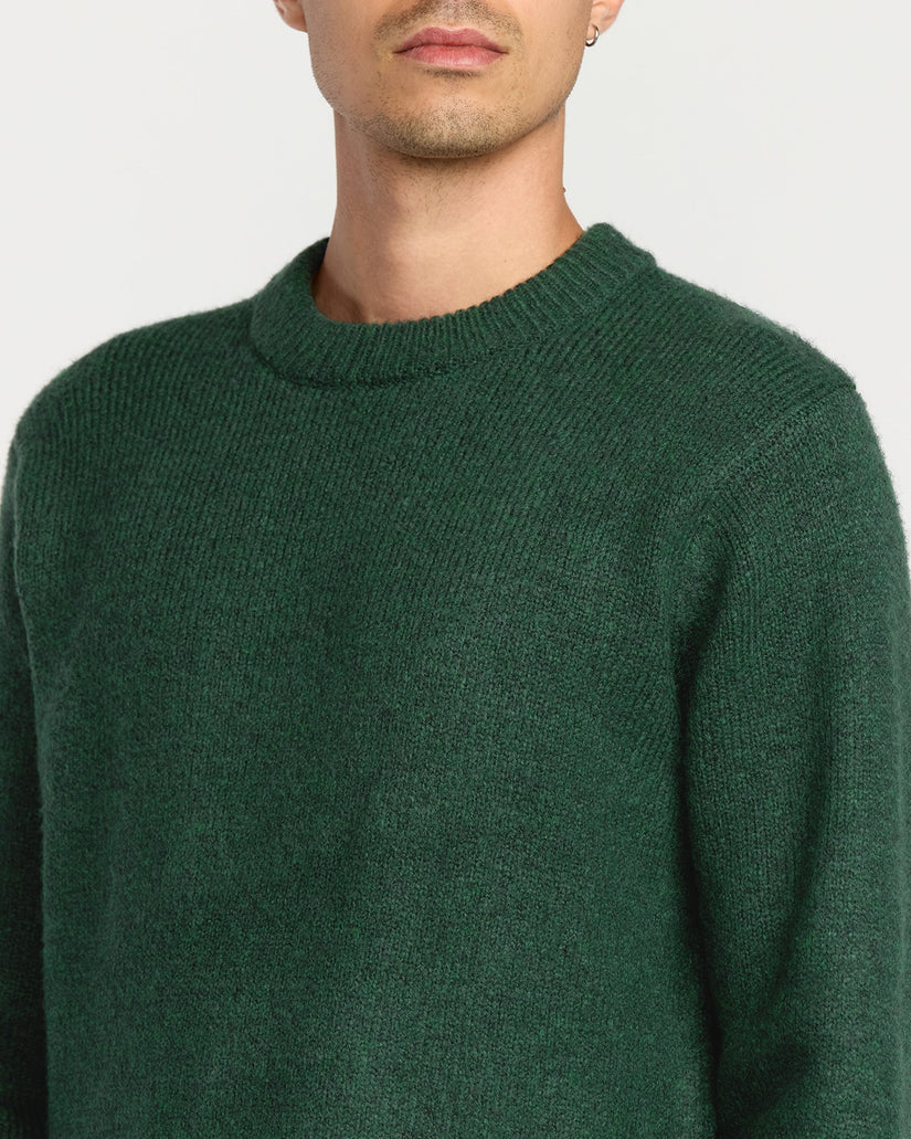 Green sweater worn by a person on a plain background