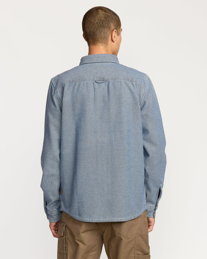 Man wearing a blue denim Volcom shirt on a white background available at Mango Surfing.