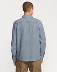 Man wearing a blue denim Volcom shirt on a white background available at Mango Surfing.