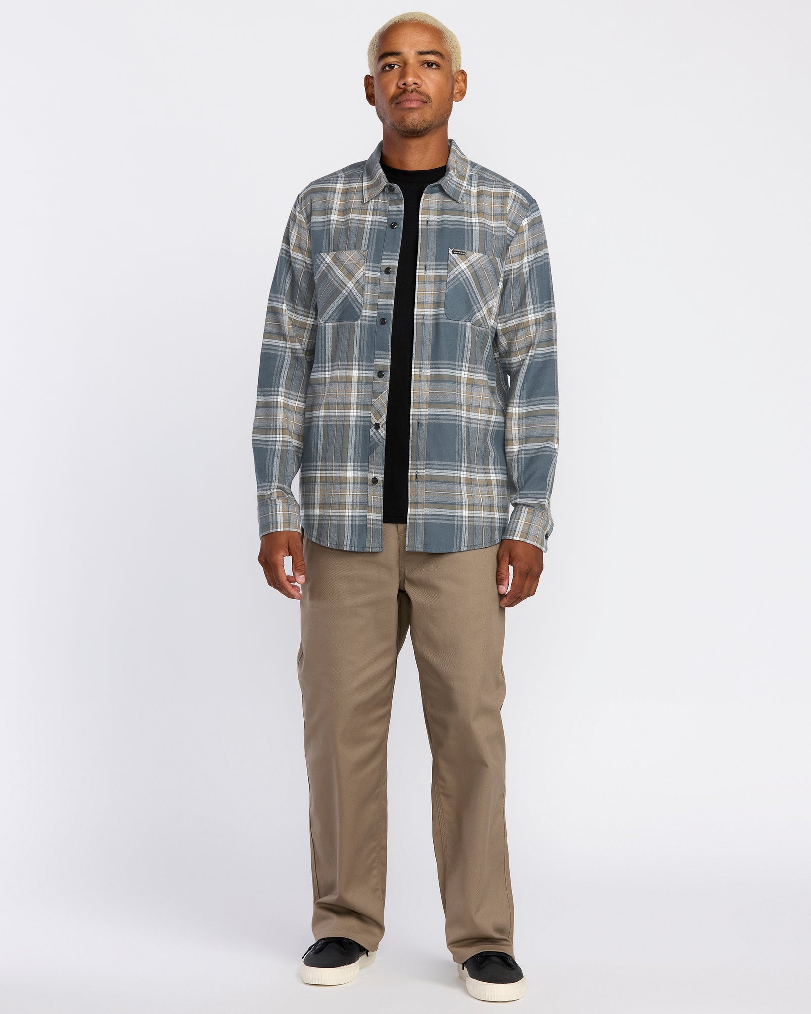 Man wearing a Volcom plaid shirt and beige pants on a white background, available at Mango Surfing.