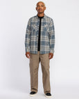 Man wearing a Volcom plaid shirt and beige pants on a white background, available at Mango Surfing.