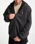 Person wearing a dark gray hoodie with a brand logo on a white background