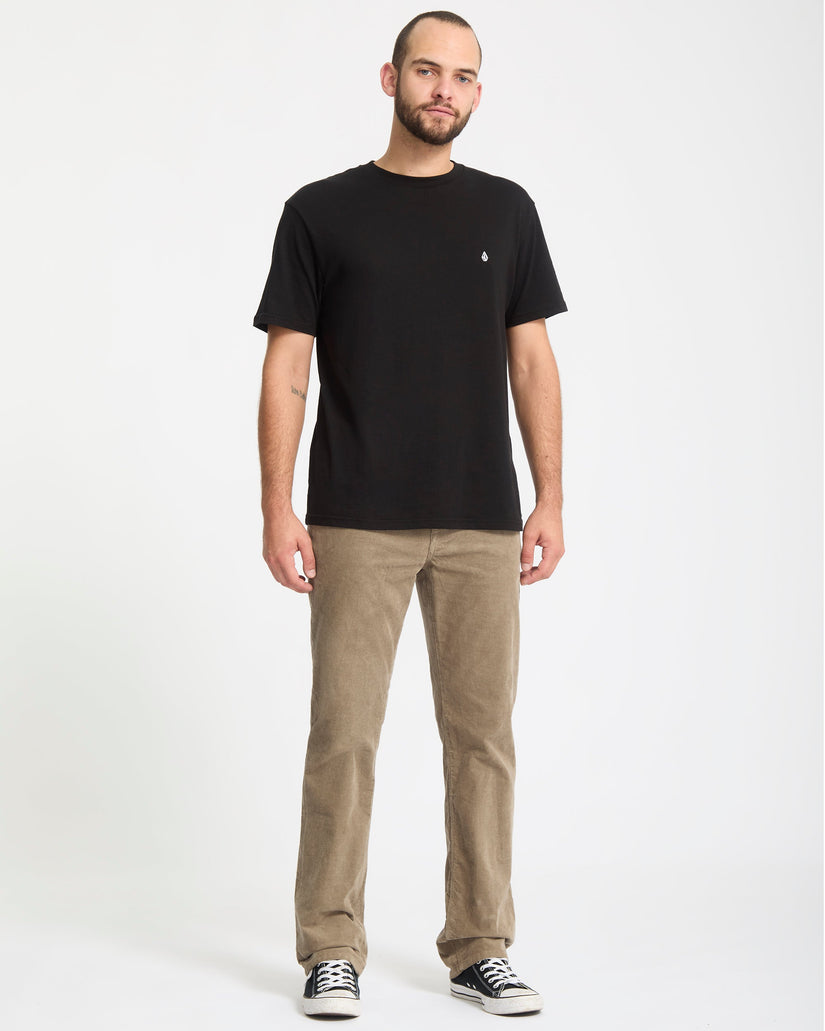 Man wearing a black t-shirt and beige pants on a white background