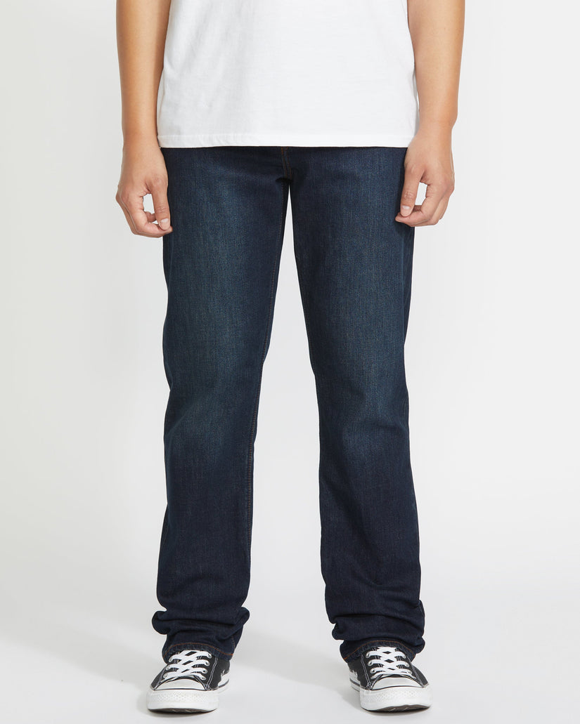 Person wearing dark blue jeans and a white shirt on a plain background