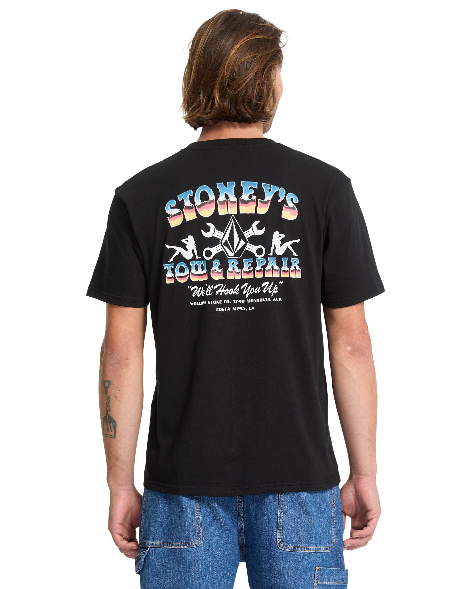 Person wearing a black t-shirt with colorful graphics and text on the back, standing against a white background.