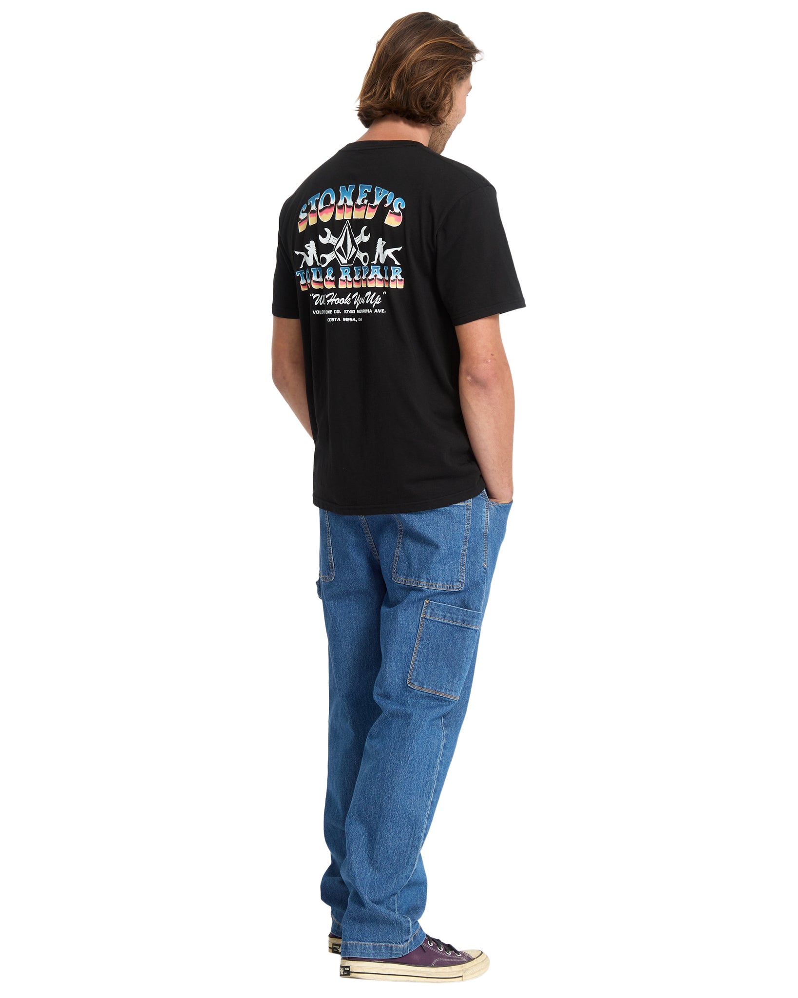 Person wearing a black t-shirt with colorful graphics and text, standing against a white background