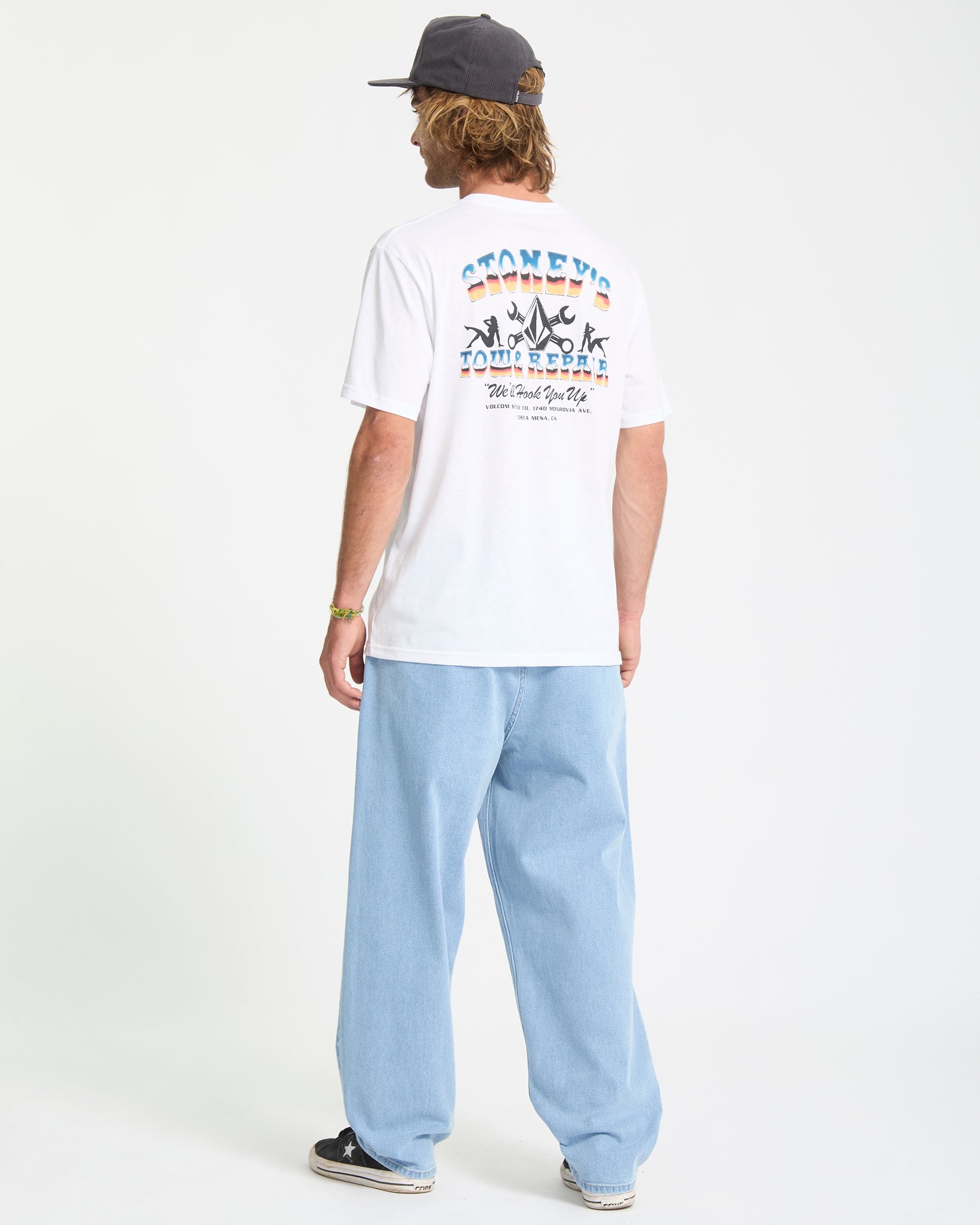 Person wearing a white t-shirt with colorful graphics and text, standing against a plain background