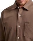 Brown button-up shirt with a Volcom logo on a white background