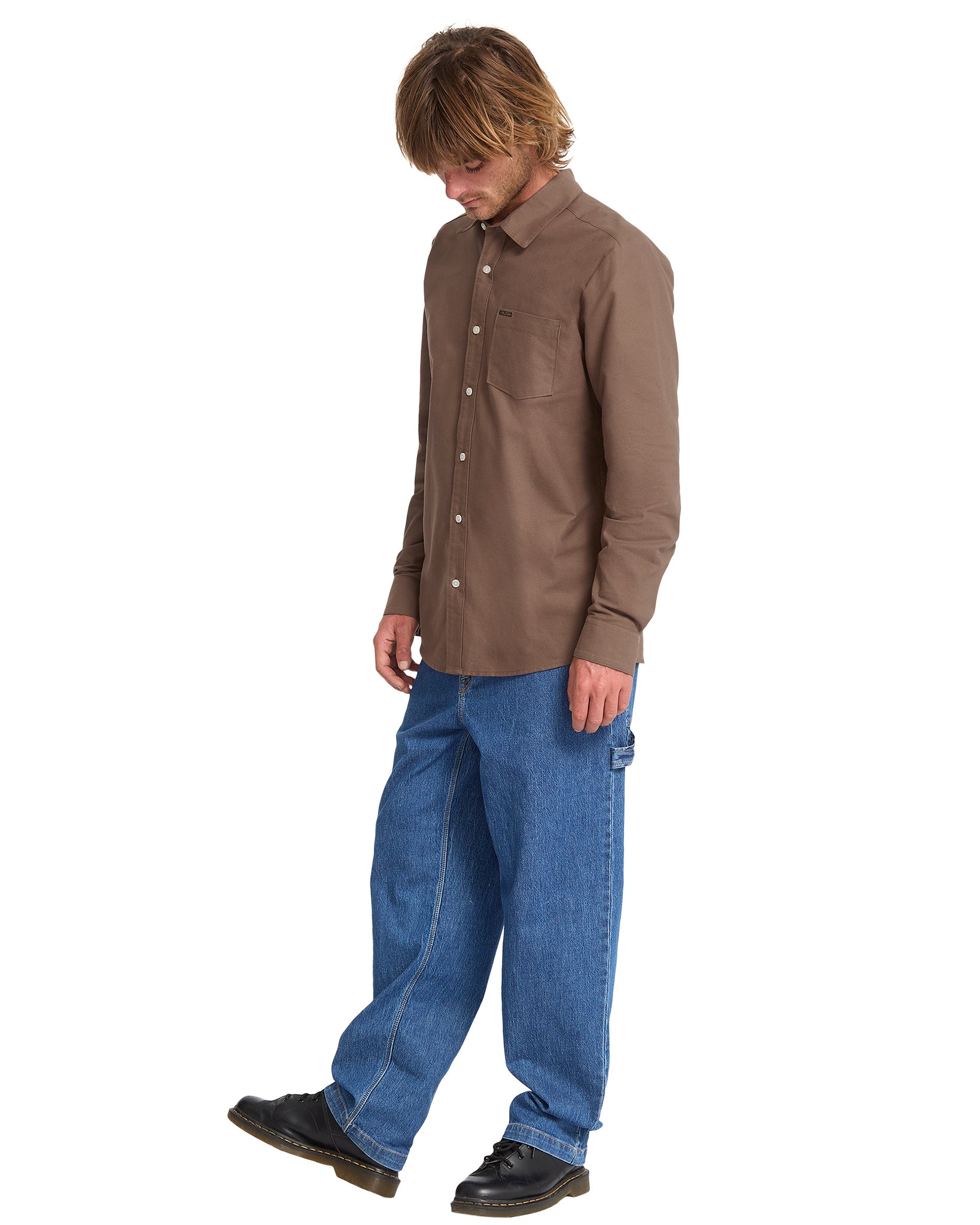 Man wearing a brown shirt and blue jeans on a white background
