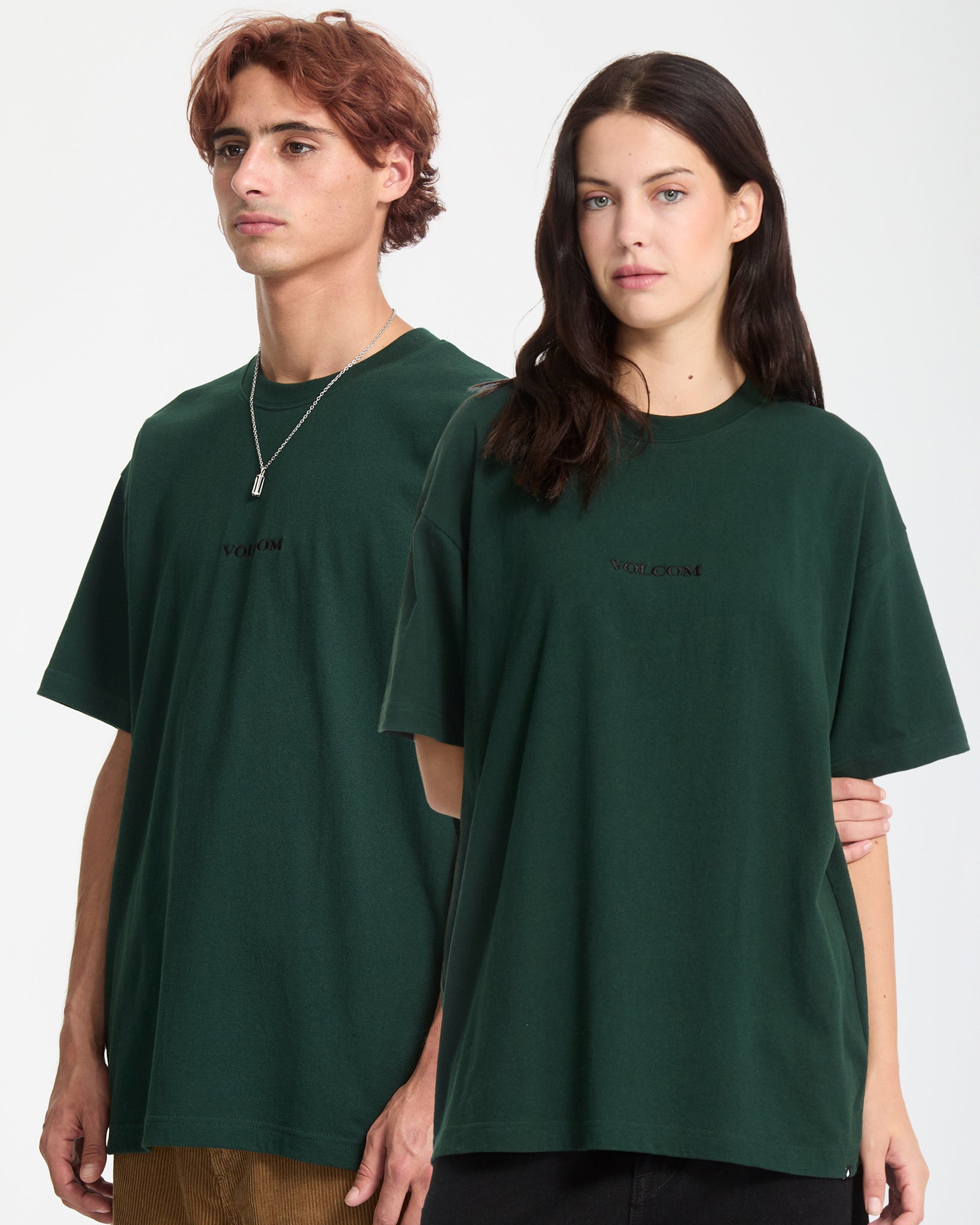 Two people wearing dark green t-shirts with a brand logo on a white background