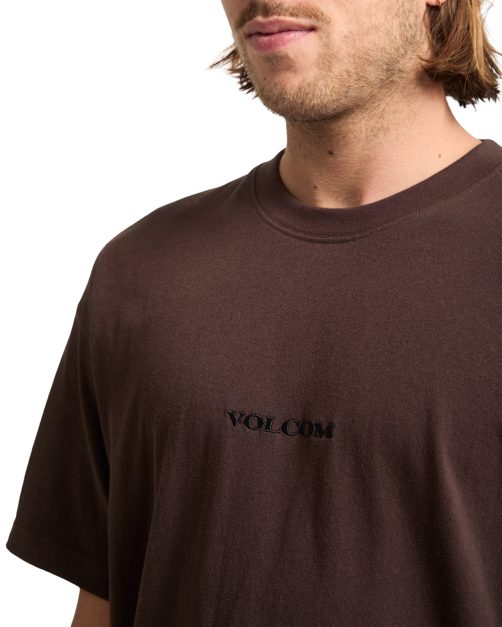 Man wearing a brown t-shirt with &#39;Volcom&#39; logo on a white background
