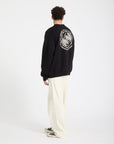 Person wearing a black Volcom sweatshirt with a white logo on the back, standing against a white background