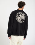 Person wearing a black sweatshirt with a white Volcom logo on the back against a white background
