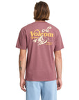 Person wearing a maroon Volcom t-shirt with a logo on the back against a white background